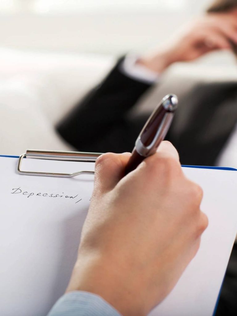 A woman sitting on the couch writing in her notebook.